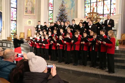 W niedzielę 26 stycznia 2025 r. w Katedrze Rzeszowskiej odbył się koncert kolęd w wykonaniu Katedralnego Chóru Chłopięco-Męskiego „Pueri Cantores Resovienses” pod dyrekcją Aleksandry Fiołek-Matuszewskiej. Tradycją chóru jest coroczne kolędowanie w Katedrze, więc nie mogło go zabraknąć także i w tym roku. Podczas koncertu wystąpiły gościnnie: Strzyżowski Chór Kameralny oraz Podkarpacki Chór Męski pod dyrekcją Grzegorza Oliwy. Koncert miał miejsce bezpośrednio po Mszy Świętej o godzinie 12:00, podczas której również zaśpiewał Katedralny Chór Chłopięco-Męski „Pueri Cantores Resovienses”. Po Eucharystii Rzeszowskie Słowiki pod dyrekcją Aleksandry Fiołek-Matuszewskiej dały piękny koncert. Na początku w wykonaniu połączonych chórów usłyszeliśmy kompozycję Dominika Lasoty „Przy wigilijnym stole”, po czym krótki rys historyczny Chóru i plan koncertu przedstawił Ryszard Bieniek – prezes Chóru. Dźwięki tak pięknych kolęd i piosenek świątecznych, jak: „Wśród nocnej ciszy”, „Carol of the bells” oraz „Jingle bells” wypełniły przestrzeń Katedry, wprowadzając zgromadzonych w świąteczny nastrój. Pięknie zabrzmiały również utwory: „Will we know him” oraz „Gdy Śliczna Panna” przy fortepianowym akompaniamencie Maksymiliana Rogóża. Następnie kolędowymi wykonaniami zachwycili słuchaczy zaproszeni goście. Podkarpacki Chór Męski wykonał kolędy: „Gore gwiazda”, „My też pastuszkowie”, „Lulajże Jezuniu”, „White Christmas”; a Strzyżowski Chór Kameralny zaprezentował pieśni: „Nad uśpioną Galileą”, „Kołysanka dla Jezusa”, „Dzisiaj w Betlejem” oraz „W dzień Bożego Narodzenia”. Dwie ostatnie kolędy zostały opracowane muzycznie przez Włodzimierza Korcza. Zarówno Podkarpackim Chórem Męskim jak i Strzyżowskim Chórem Kameralnym dyrygował Grzegorz Oliwa, który jest absolwentem Krakowskiej Akademii Muzycznej z tytułem profesora sztuk muzycznych. Prof. Grzegorz Oliwa był w latach 1988-1990 także chórzystą Katedralnego Chóru „Pueri Cantores Resovienses”. W kolejnej części koncertu męska część Chóru Pueri Cantores Resovienses, czyli tenory i basy, wykonała pod dyrekcją Aleksandry Fiołek-Matuszewskiej kolędy „W żłobie leży” oraz „Mizerna cicha”. Na zakończenie koncertu zabrzmiał jeszcze utwór „Powiadają aniołkowie”, który zgromadzona publiczność mogła usłyszeć w wykonaniu połączonych chórów męskich pod dyrekcją Grzegorza Oliwy. Po koncercie przyszedł czas na podsumowanie i podziękowania. Głos zabrał Ryszard Bieniek – wieloletni chórzysta i obecny prezes Katedralnego Chóru Chłopięco-Męskiego. Na zakończenie tego muzycznego wydarzenia zasłużeni artyści zostali uhonorowani kwiatami, a publiczność wyraziła swoją wdzięczność gromkimi brawami. Kolędę „Bóg się rodzi”, uważaną za królową wszystkich kolęd, połączone chóry wykonały wspólnie z publicznością, tworząc niezapomniane zakończenie tego spotkania. Podsumowując, koncert w Katedrze Rzeszowskiej był nie tylko muzycznym świętem, ale także wyjątkowym doświadczeniem duchowym, które zjednoczyło zgromadzonych w radosnym śpiewie i refleksji. Patronat nad koncertem objął bp Jan Wątroba. Do zobaczenia na następnych koncertach! ks. Julian Wybraniec fot. Patrycja Pelczar Reszko