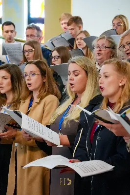 Ubogacenie duchowe, wyjątkowe opracowania pieśni, nowa wiedza o muzyce w liturgii i otwarta, domowa atmosfera – tak pierwszy weekend października wspominają uczestnicy Warsztatów Muzyki Liturgicznej „Na dobry początek” zorganizowanych przy Katedrze Rzeszowskiej.

Warsztaty odbywające się od 4 do 6 października zorganizowała Katedralna Schola Liturgiczna na czele z koordynatorem ks. Julianem Wybrańcem – wikariuszem parafii katedralnej w Rzeszowie. Było to pierwsze tego typu wydarzenie w historii rzeszowskiej parafii Najświętszego Serca Pana Jezusa. W warsztatach wzięło udział ponad 50 osób z całej Polski, w różnym wieku i z różnym doświadczeniem muzycznym; zarówno wieloletni chórzyści i muzycy, prowadzący schole, członkowie wspólnot i grup parafialnych, jak i śpiewający zwyczajnie zainteresowani muzyką liturgiczną.

Prowadzącym warsztaty był Wiktor Lorens – kompozytor, dyrygent i aranżer, absolwent Akademii Muzycznej w Krakowie, prowadzący zespół wokalny adFontem przy jasielskim sanktuarium św. Antoniego, współpracujący z chórami i zespołami wokalno-instrumentalnymi w Polsce. Za opiekę duchową oraz współprowadzenie prób w sekcjach głosowych odpowiedzialny był o. Sylwester Kurzyna OFMConv, franciszkanin obecnie posługujący w Jaśle.

Wydarzenie rozpoczęło się w piątkowe popołudnie rejestracją uczestników, rozśpiewaniem oraz rozczytaniem pierwszych utworów w głosach i łączeniem ich w chórze. Najintensywniejsza praca miała miejsce w sobotę, kiedy chórzyści pod opieką Wiktora szlifowali warsztat wokalny i emisję głosu, opierając się na przygotowanych pieśniach, oraz ćwiczyli utwory na niedzielną Mszę Świętą. W repertuarze znalazły się głównie pieśni w ciekawych opracowaniach Wiktora Lorensa, jak „Źródło życia”, „Różańcowa Pani nieba ziemi”, „Maria Regina mundi” czy „Pozdrowienie błogosławionej Dziewicy Maryi”.

Nie zabrakło troski o stronę duchową. Uczestnicy mieli okazję wysłuchać konferencji o. Sylwestra, skorzystać z sakramentu pokuty oraz wziąć udział we wspólnych modlitwach. A ponieważ obok ducha ważne jest też ciało, w przerwach przy wspólnej herbacie i kawie można było nieco odpocząć, nawiązać nowe znajomości i bliżej się poznać.

Punktem kulminacyjnym warsztatów była niedzielna Msza Święta o godz. 12:00, podczas której uczestnicy podzielili się owocami przeżytego czasu poprzez śpiew w czasie liturgii oraz krótki koncert po jej zakończeniu.

Jedną z przewodnich myśli organizatorów warsztatów była sentencja, iż w każdym działaniu najważniejszy jest początek. Warsztaty Muzyki Liturgicznej przy Katedrze Rzeszowskiej z pewnością były ubogacającym czasem, który wyrył w uczestnikach nie tylko wyjątkowe wspomnienia, ale również motywację do działania, dołączenia do wspólnoty czy wzbogacenia repertuaru o nowo poznane pieśni w działających przy parafiach uczestników scholach i chórach. Niech Bóg będzie uwielbiony za ten październikowy weekend przepełniony muzyką i modlitwą.

Angelika Karnasiewicz

fot. Łukasz Lewandowski