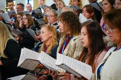 Ubogacenie duchowe, wyjątkowe opracowania pieśni, nowa wiedza o muzyce w liturgii i otwarta, domowa atmosfera – tak pierwszy weekend października wspominają uczestnicy Warsztatów Muzyki Liturgicznej „Na dobry początek” zorganizowanych przy Katedrze Rzeszowskiej.

Warsztaty odbywające się od 4 do 6 października zorganizowała Katedralna Schola Liturgiczna na czele z koordynatorem ks. Julianem Wybrańcem – wikariuszem parafii katedralnej w Rzeszowie. Było to pierwsze tego typu wydarzenie w historii rzeszowskiej parafii Najświętszego Serca Pana Jezusa. W warsztatach wzięło udział ponad 50 osób z całej Polski, w różnym wieku i z różnym doświadczeniem muzycznym; zarówno wieloletni chórzyści i muzycy, prowadzący schole, członkowie wspólnot i grup parafialnych, jak i śpiewający zwyczajnie zainteresowani muzyką liturgiczną.

Prowadzącym warsztaty był Wiktor Lorens – kompozytor, dyrygent i aranżer, absolwent Akademii Muzycznej w Krakowie, prowadzący zespół wokalny adFontem przy jasielskim sanktuarium św. Antoniego, współpracujący z chórami i zespołami wokalno-instrumentalnymi w Polsce. Za opiekę duchową oraz współprowadzenie prób w sekcjach głosowych odpowiedzialny był o. Sylwester Kurzyna OFMConv, franciszkanin obecnie posługujący w Jaśle.

Wydarzenie rozpoczęło się w piątkowe popołudnie rejestracją uczestników, rozśpiewaniem oraz rozczytaniem pierwszych utworów w głosach i łączeniem ich w chórze. Najintensywniejsza praca miała miejsce w sobotę, kiedy chórzyści pod opieką Wiktora szlifowali warsztat wokalny i emisję głosu, opierając się na przygotowanych pieśniach, oraz ćwiczyli utwory na niedzielną Mszę Świętą. W repertuarze znalazły się głównie pieśni w ciekawych opracowaniach Wiktora Lorensa, jak „Źródło życia”, „Różańcowa Pani nieba ziemi”, „Maria Regina mundi” czy „Pozdrowienie błogosławionej Dziewicy Maryi”.

Nie zabrakło troski o stronę duchową. Uczestnicy mieli okazję wysłuchać konferencji o. Sylwestra, skorzystać z sakramentu pokuty oraz wziąć udział we wspólnych modlitwach. A ponieważ obok ducha ważne jest też ciało, w przerwach przy wspólnej herbacie i kawie można było nieco odpocząć, nawiązać nowe znajomości i bliżej się poznać.

Punktem kulminacyjnym warsztatów była niedzielna Msza Święta o godz. 12:00, podczas której uczestnicy podzielili się owocami przeżytego czasu poprzez śpiew w czasie liturgii oraz krótki koncert po jej zakończeniu.

Jedną z przewodnich myśli organizatorów warsztatów była sentencja, iż w każdym działaniu najważniejszy jest początek. Warsztaty Muzyki Liturgicznej przy Katedrze Rzeszowskiej z pewnością były ubogacającym czasem, który wyrył w uczestnikach nie tylko wyjątkowe wspomnienia, ale również motywację do działania, dołączenia do wspólnoty czy wzbogacenia repertuaru o nowo poznane pieśni w działających przy parafiach uczestników scholach i chórach. Niech Bóg będzie uwielbiony za ten październikowy weekend przepełniony muzyką i modlitwą.

Angelika Karnasiewicz

fot. Łukasz Lewandowski